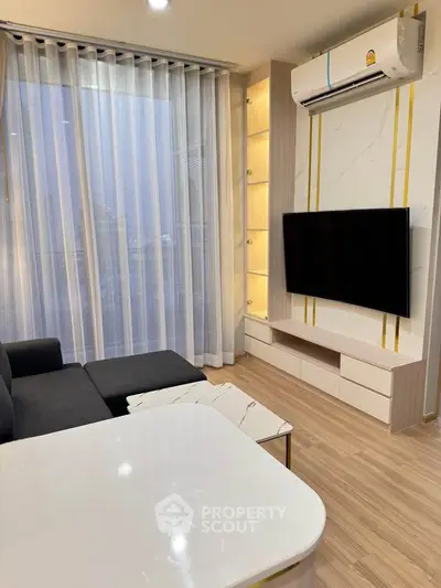 Modern living room with sleek furniture and large TV, featuring elegant curtains and stylish decor.