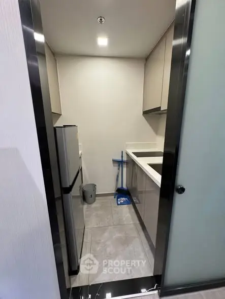 Compact modern kitchen with sleek cabinetry and stainless steel appliances in a cozy apartment.