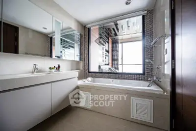 Luxurious bathroom with modern fixtures and large mirror, featuring a spacious bathtub and elegant design.