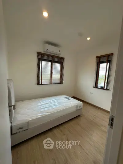 Cozy bedroom with natural light and minimalist design, featuring a single bed and wooden flooring.