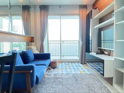 Modern living room with blue sofa, large window, and stylish shelving unit.