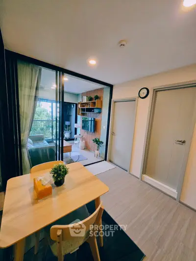 Modern apartment interior with dining area and view of living room and balcony.
