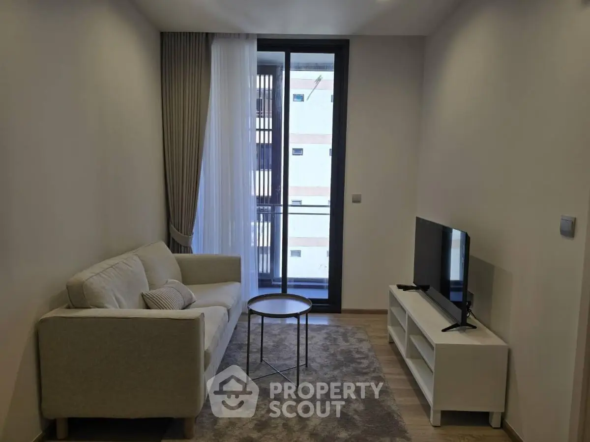 Modern living room with cozy sofa and TV, featuring a large window for natural light.