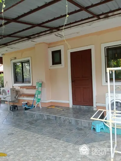 Charming home entrance with tiled patio and laundry area, featuring a washing machine and air conditioning unit.