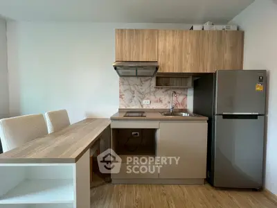 Modern kitchen with sleek cabinetry, compact dining area, and stainless steel appliances.