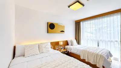 Bright and cozy bedroom with twin beds and large window in modern apartment.