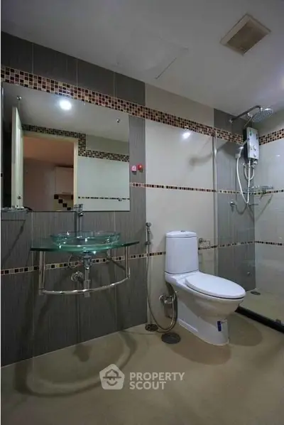 Modern bathroom with glass sink and shower in stylish apartment.