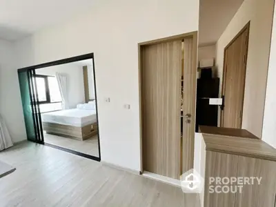 Modern bedroom with sliding glass doors and wooden flooring, featuring a cozy bed and ample natural light.