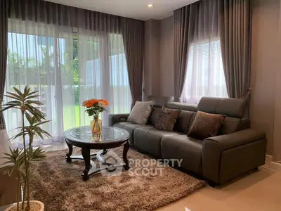 Elegant living room with plush sofa, stylish curtains, and garden view.