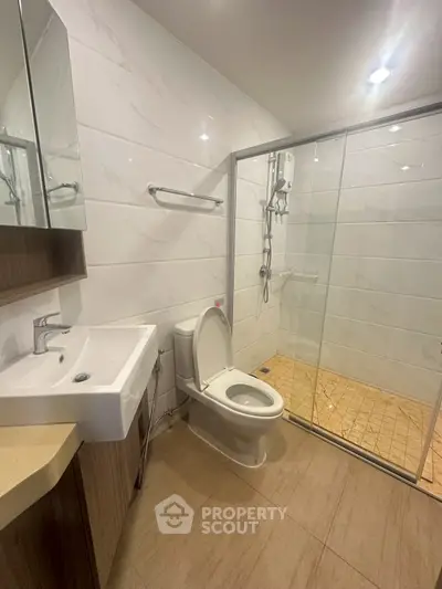 Modern bathroom with glass shower and sleek fixtures in contemporary apartment.