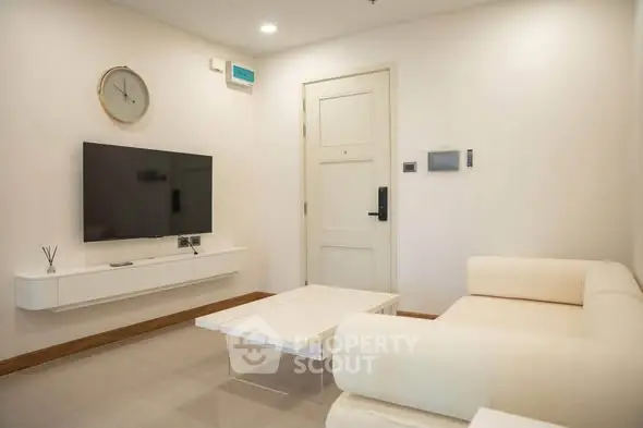 Modern living room with sleek furniture and wall-mounted TV in a cozy apartment.