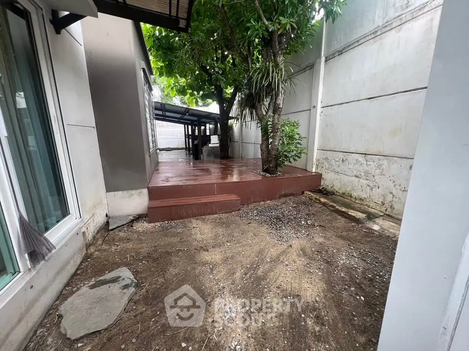 Spacious outdoor area with wooden deck and lush greenery, perfect for relaxation and entertainment.