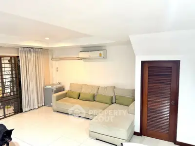 Spacious living room with cozy sectional sofa and air conditioning, perfect for relaxation.