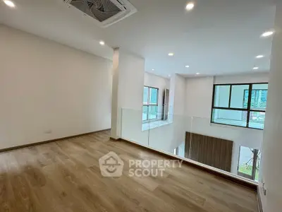 Spacious modern living area with large windows and wooden flooring, perfect for natural light lovers.