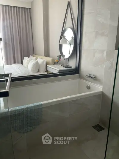 Modern bathroom with bathtub and view into stylish bedroom