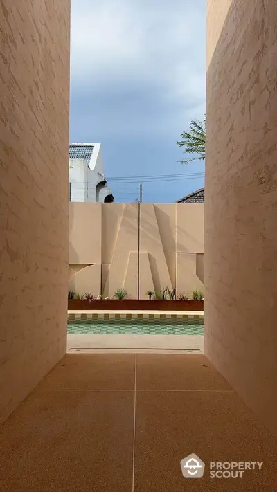 Modern architectural entrance leading to a stylish pool area with unique wall design.