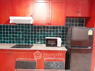 Modern kitchen with red cabinetry, black fridge, and microwave