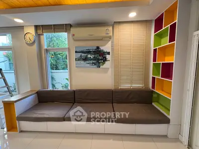Modern living room with colorful shelves and cozy sofa, featuring large windows and air conditioning.