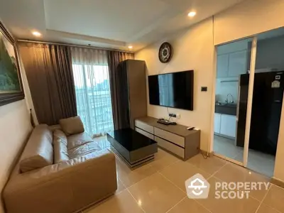 Modern living room with sleek furniture and large TV, adjacent to a contemporary kitchen.