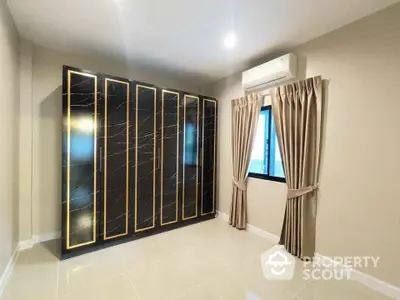 Modern bedroom with sleek black wardrobe and air conditioning unit