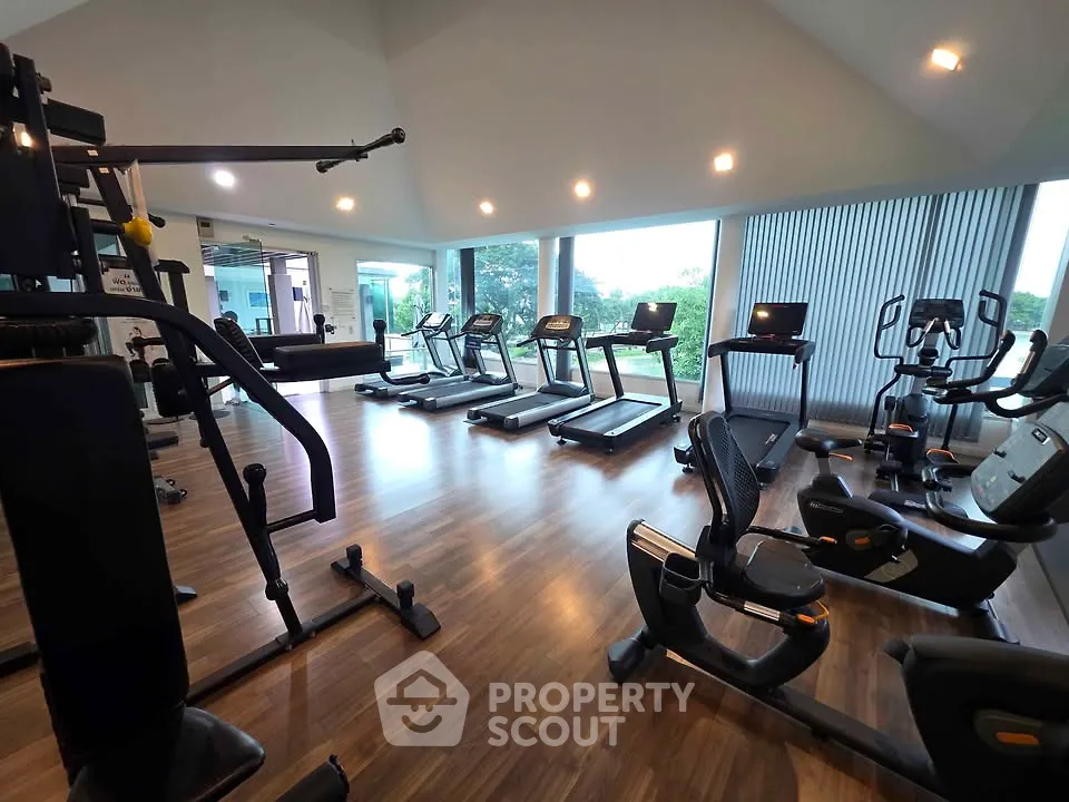 Spacious gym with modern equipment and large windows offering scenic views.
