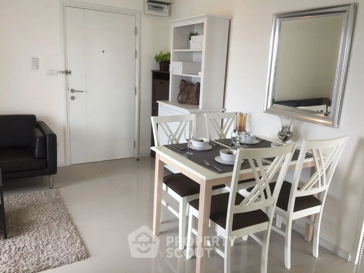 Modern dining area with elegant white chairs and stylish decor in a cozy apartment.