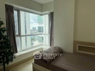 Cozy bedroom with large windows offering city views, perfect for urban living.