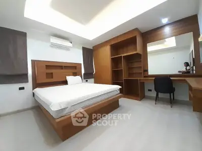 Modern bedroom with wooden furniture and built-in desk, featuring a minimalist design.