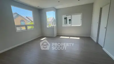 Bright empty room with large windows and wooden flooring, perfect for customization.