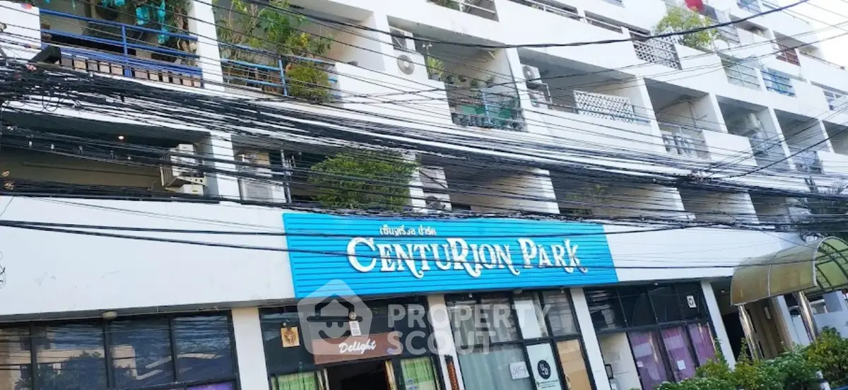 Modern apartment building exterior with balconies and lush greenery in urban setting.