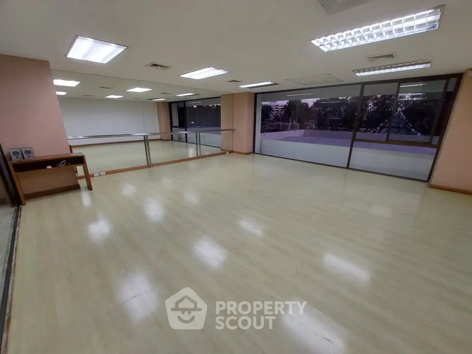 Spacious room with large windows and wooden flooring, ideal for office or studio space.