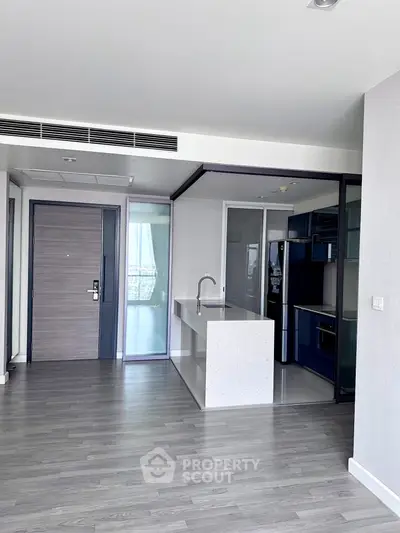 Modern open-layout kitchen with sleek design and spacious living area in a contemporary apartment.