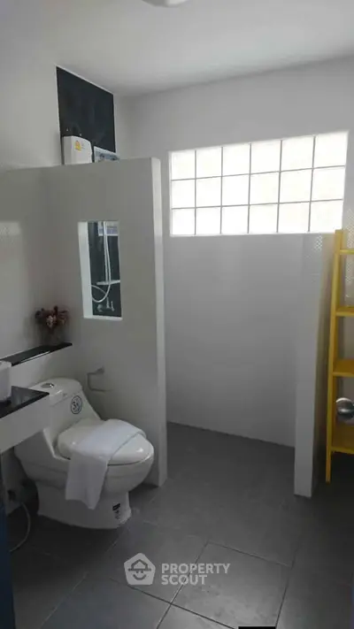 Modern bathroom with sleek design and natural light from glass block window.
