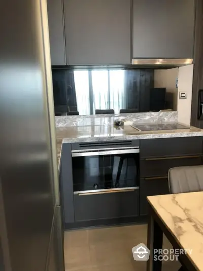 Modern kitchen with sleek cabinetry and built-in oven in luxury apartment