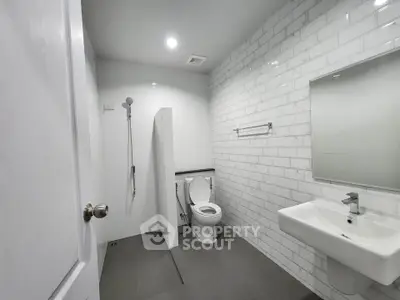 Modern minimalist bathroom with sleek white tiles and contemporary fixtures.