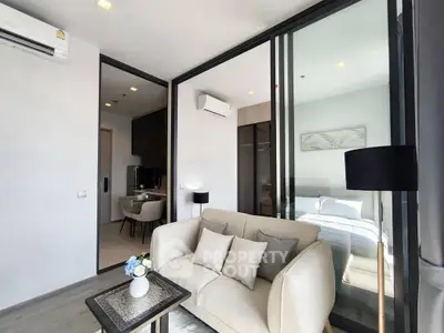 Modern living room with cozy sofa and glass partition leading to bedroom in stylish apartment.
