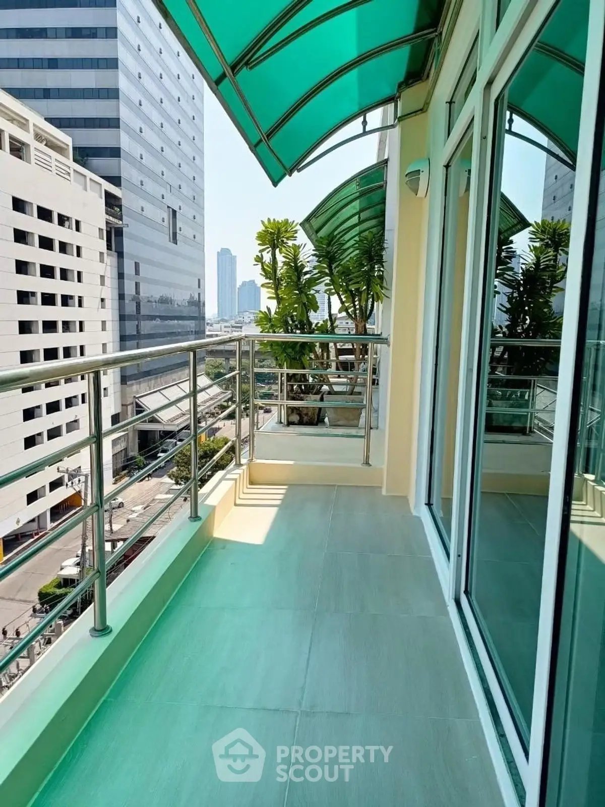 Spacious balcony with city view and modern glass railing in urban high-rise building.