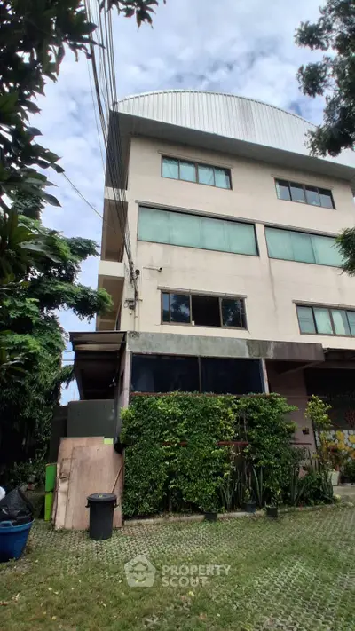 Modern multi-story building with lush greenery and spacious surroundings.