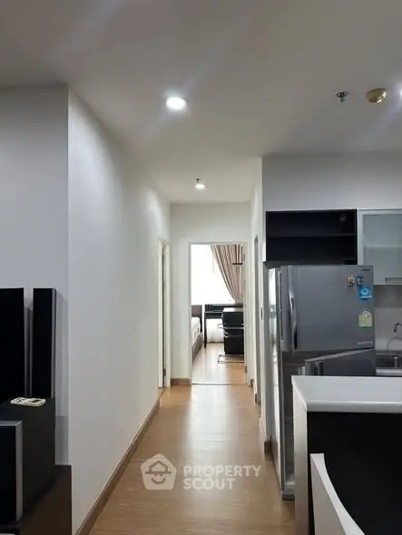 Modern apartment interior with sleek kitchen and hallway leading to bedroom.