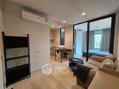 Modern open-plan living room with cozy sofa, sleek kitchen, and bright bedroom in a stylish apartment.