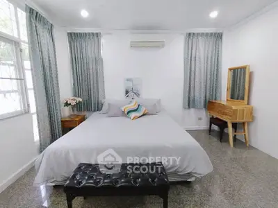 Spacious bedroom with elegant decor and natural light, featuring a cozy bed and stylish furniture.