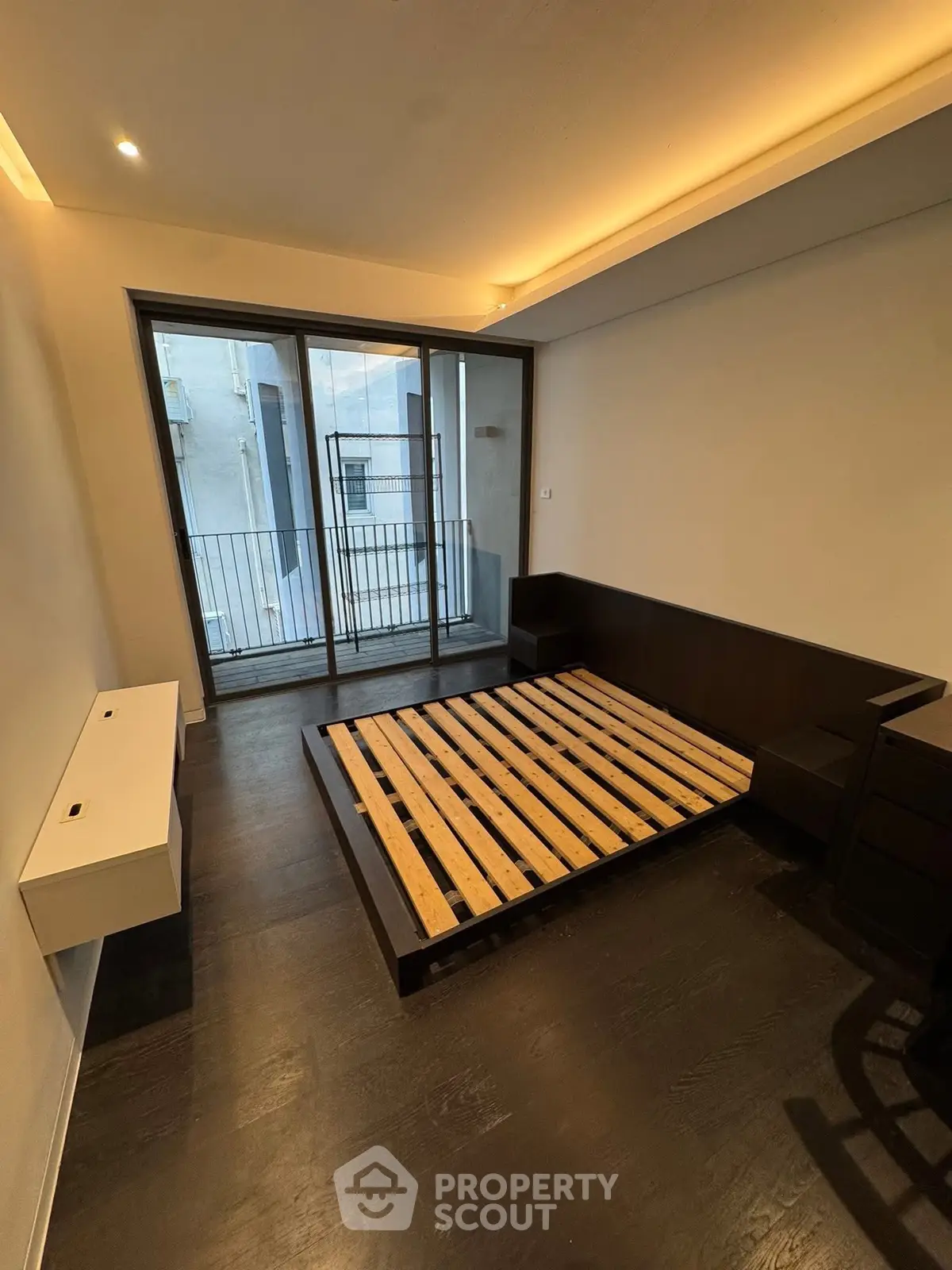 Modern bedroom with sleek dark flooring and large glass doors leading to a balcony.