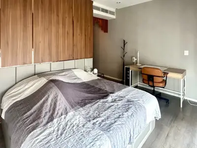 Modern bedroom with stylish decor and workspace, featuring wooden accents and cozy ambiance.