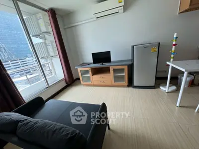 Modern living room with balcony view, compact furniture, and sleek design in urban apartment.