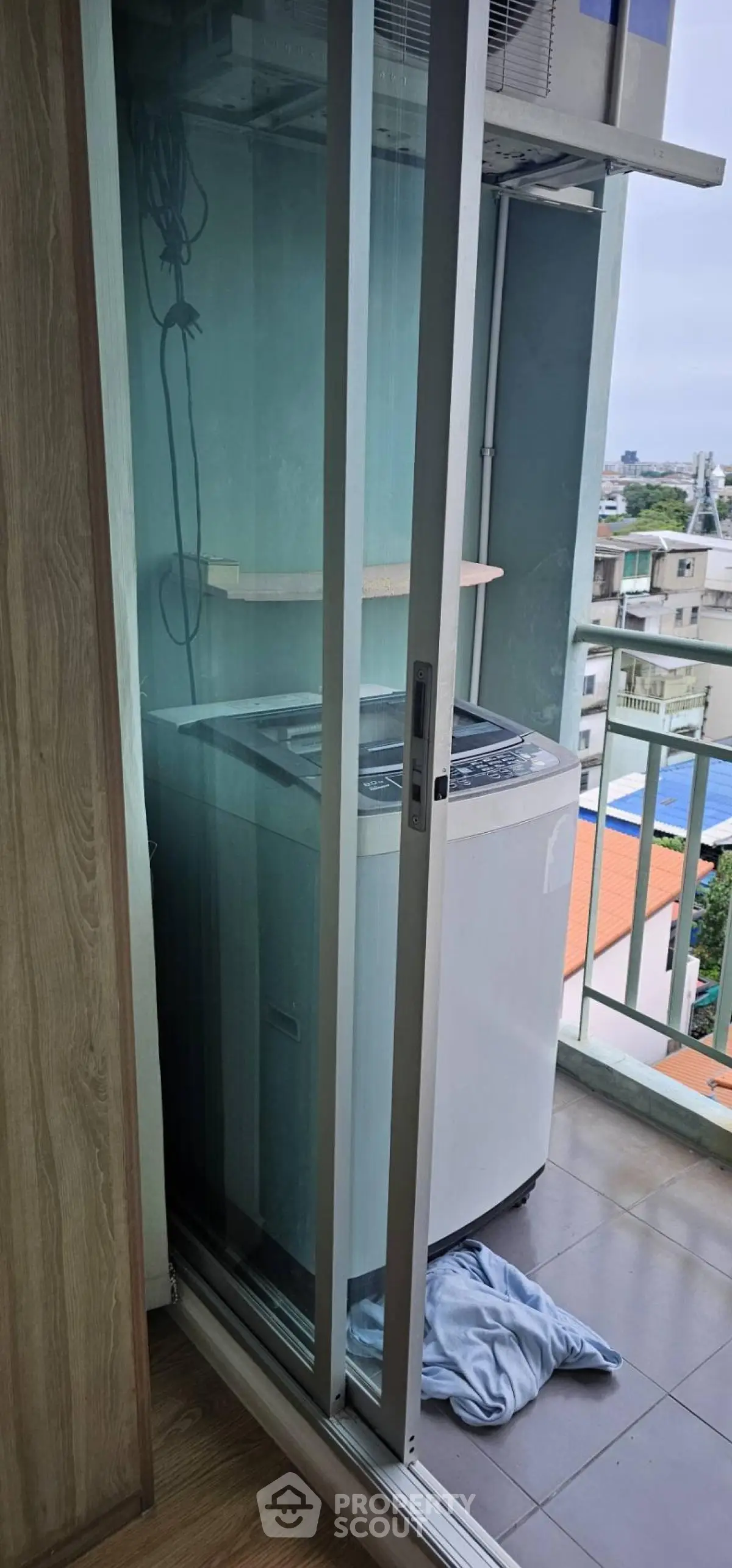 Compact balcony with washing machine and city view, ideal for urban living.