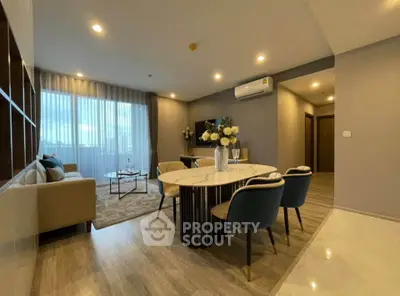 Modern living room with elegant dining area and cozy seating, featuring stylish decor and ambient lighting.