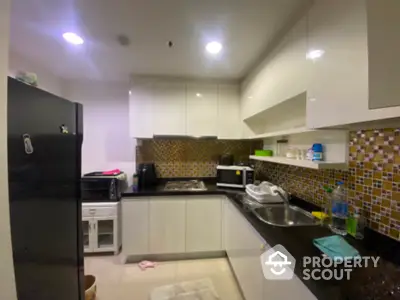 Modern kitchen with sleek cabinets and mosaic backsplash in a cozy apartment.