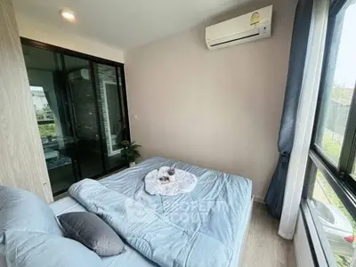 Cozy bedroom with large window and air conditioning, featuring modern decor and natural light.
