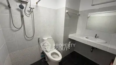 Modern bathroom with sleek fixtures and tiled walls, featuring a shower and toilet.