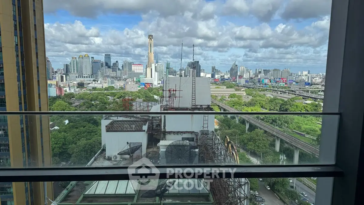 Stunning cityscape view from a high-rise balcony with lush greenery and urban skyline.